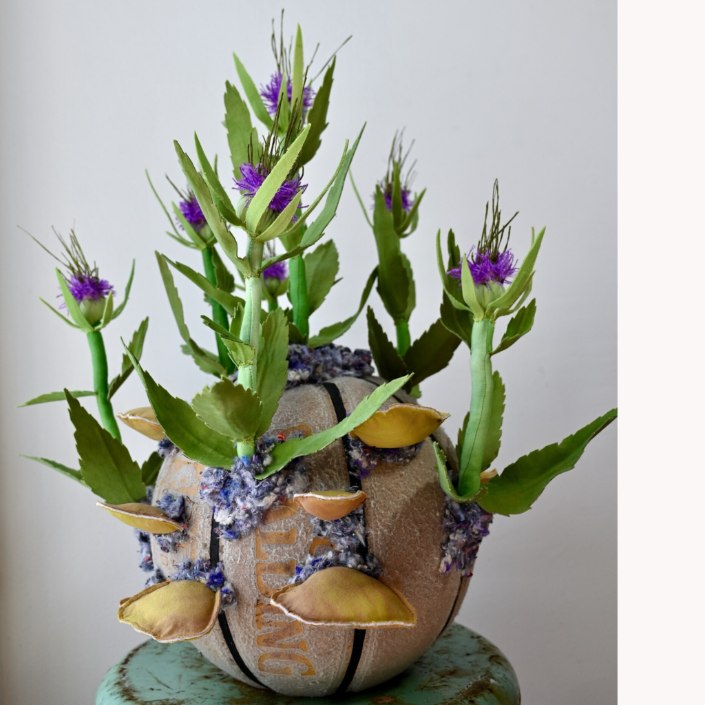 Alissa Alfonso, Teasel & Turkey Tail Mushrooms, 2026, hand—dyed textile waste, reused fiber-fill, embroidery floss, thread, textile stabilizer; base: reclaimed basketball, shredded textile shoddy, 21 x 18 x 18 in.